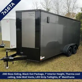 Enclosed dual-axle cargo trailer in dark gray with diamond-plate front, hitched to a tow bar on grass; intended for hauling equipment. It features a tall, boxy cargo area and side vent panels.