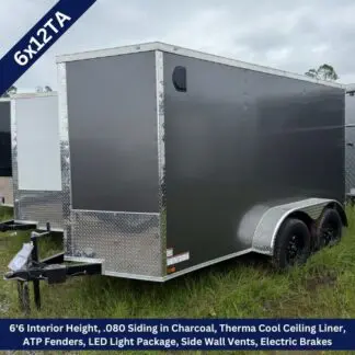 Charcoal 6x12 enclosed trailer with dual axles and diamond plate trim on a grassy lot, ready for towing by a hitch.
