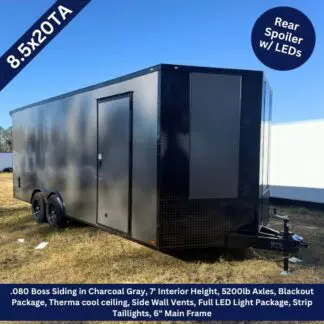 Black enclosed trailer with dual axles, side entry door, and front hitch on a grassy lot; labeled 8.5x20TA with rear LED spoiler paneling.