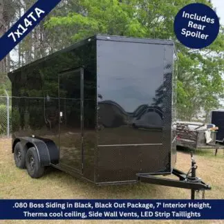 Black enclosed cargo trailer with tandem axles on grass, front hitch, and side entry door; promotional badges note 7' interior height and rear spoiler inclusion.