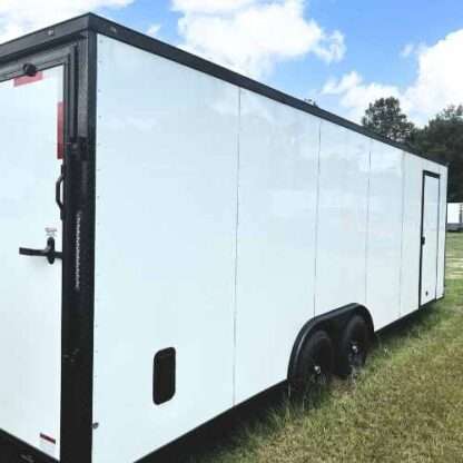 A white trailer with black trim parked in the grass.