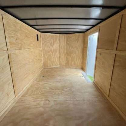 A large trailer with plywood walls and ceiling.