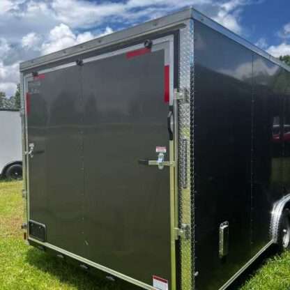 A black trailer with a door open on the grass.