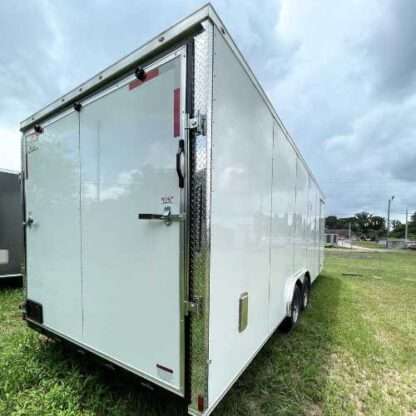 A white trailer with a door open on the grass.