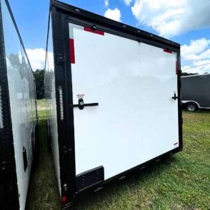 A white and black trailer parked in the grass.