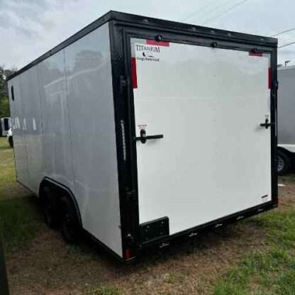 A white trailer with black trim parked in the grass.