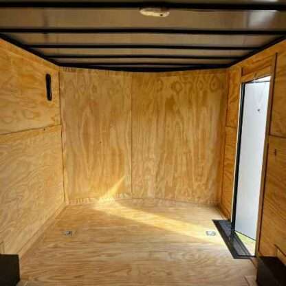 A room with plywood walls and a door.