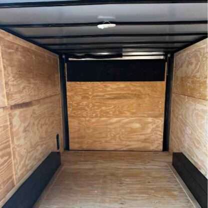 A large trailer with plywood walls and black trim.