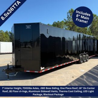 Long glossy black enclosed trailer on a dirt lot under a clear blue sky; features banners note 8.5x36TA and 7' interior height, 7000 lb axles, aluminum sidewalls, LED lighting, and an 8' main frame included.