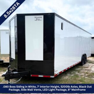 Enclosed white cargo trailer with black front panels and dual axles parked on a gravel lot.