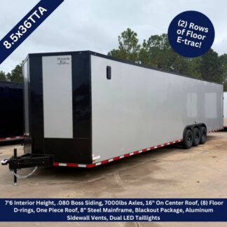 Enclosed dual-axle cargo trailer on a dirt lot; highlights two rows of Floor E-trac, white with black front, side vents and red-white reflective trim along the base.